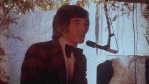 Lennie Heppell speaking into a microphone at a nightclub