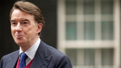 Peter Mandelson as he arrives in Downing Street to take up his new role as business secretary in 2008. He is wearing a blue suit and tie and red sweater.