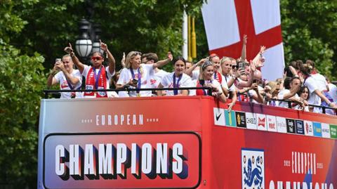 The bus carrying the England women's national football team drives along the Mall during the homecoming victory parade near Buckingham Palace 