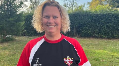 The secretary of Richmond Dales Swimming Club, wearing a club top, smiling at the camera