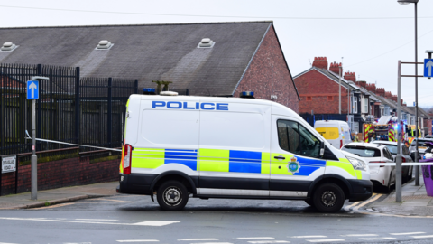 A police van sits in front of a cordon on Douglas Road in Anfield. A fire engine can be seen behind the blue and white police tape