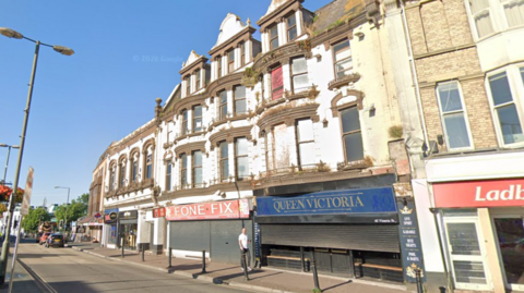 The image shows a row of older, slightly run-down buildings along a town centre street.