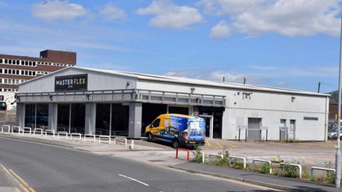 A unit with Master Flex signage on it and a van parked outside