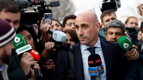 Luis Rubiales surrounded by media outside of the court