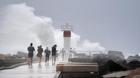 People gather to watch huge waves batter the Gold Coast ahead of cyclone Alfred's landfall