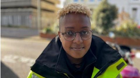 Lumi, a civil enforcement officer, is standing in a busy Hove street