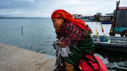 a woman sits looking sad beside a bay