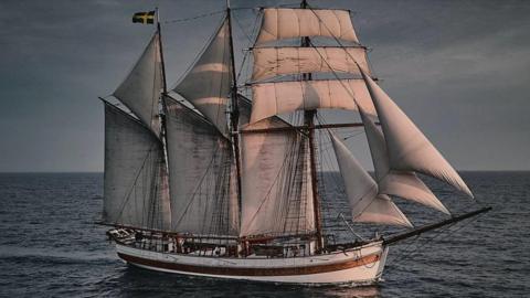 A tall ship with 11 white sails on a body of water