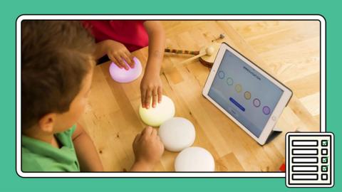 Photo of two young children using adapted buttons to explore music on a tablet.