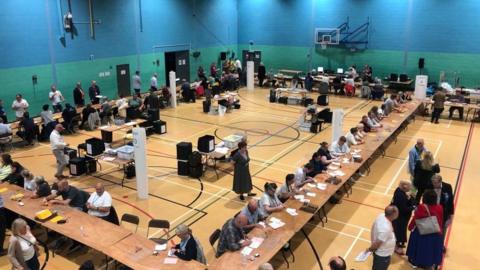 A leisure centre where votes were counted in the elections for the Farnham and Bordon and Godalming and Ash constituencies. People sit at tables to count the votes.