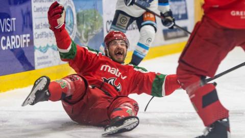 Cardiff Devils Riley Brandt on his back on the ice grinning celebrates with arms spread wide