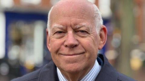 A picture of West Berkshire Council leader Jeff Brooks standing on Newbury's Northbrook Street. He's wearing a blue and white striped shirt and a striped tie.