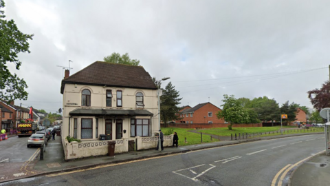 A two-storey cream building on the corner of two residential streets 