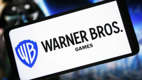 Warner Bros Games logo displayed on a white phone screen in front of a Star Wars themed background. 