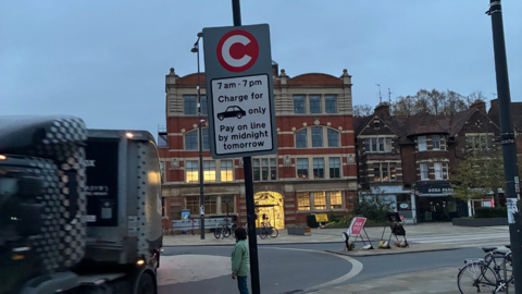 A grey and white road sign saying motorists can pay the fee "on line", instead of "online"
