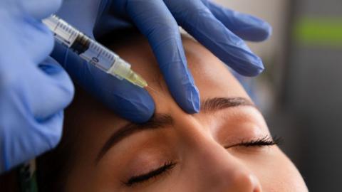 A woman has a substance injected between her eyebrows