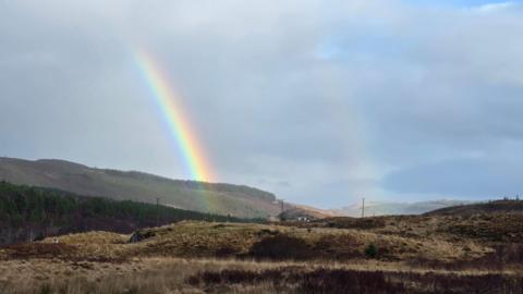 A double rainbow in clouds over fields