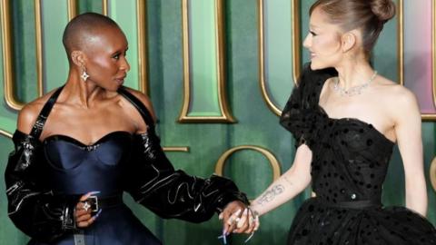 Cynthia Erivo and Ariana Grande are pictured holding hands and smiling at each other as they arrived for the European premiere in London of Wicked: For Good.