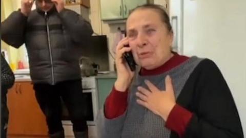 Nazer Daletskyi's mother Nataliya clutches her hand to her chest as she speaks on the phone to her son