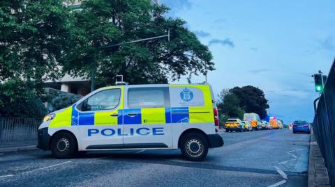 Numerous police vehicles at the scene of an incident in Aberdeen, a police van is parked across the road.