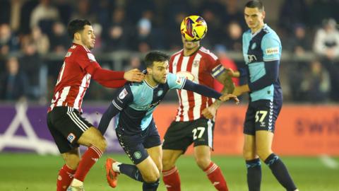 Wycombe's Daniel Harvie is challenged by Exeter's Jack Aitchison at St James Park