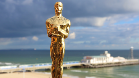 A golden Oscar statuette with Bournemouth beach and pier in the background.