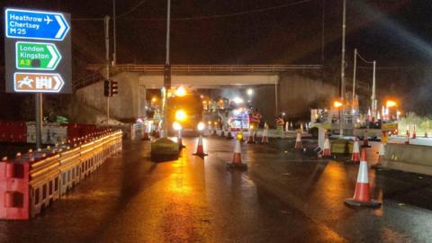 Workers at the M25 Junction 10, with cones and National Highways lorries in the road