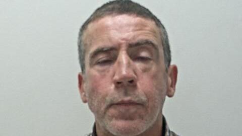 A police issue picture of Waite, he has short grey hair and is blinking at the camera