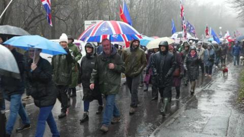 People protest in the rain. 