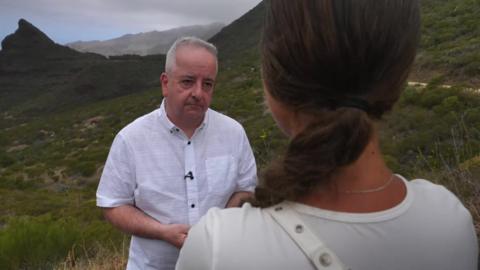 BBC reporter Nick Garnett speaking to Lucy Law, her back is to the camera