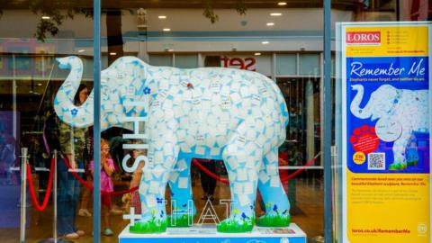 A piece of artwork designed in the shape of an elephant which is covered in white spaces for people to add the names of missed family and friends