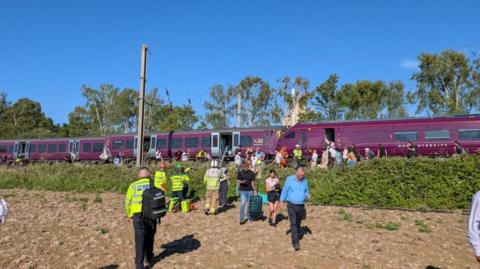 Train with people leaving the carriages and emergency services in attendance
