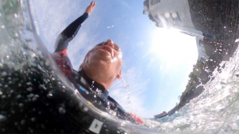 Man in a wetsuit in the sea, with his head above water