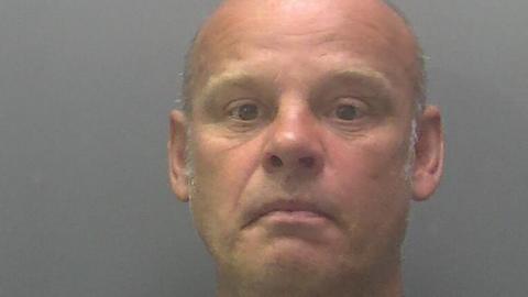 Custody image of Gary Smith, a balding man with light-grey hair on the top and sides of his head.