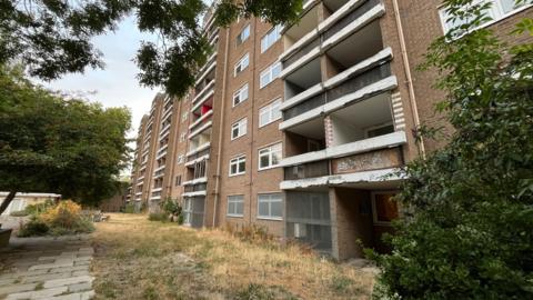 General view of a block of council flats, a brick building which is seven storeys high.