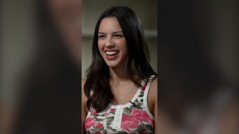 Olivia looks off camera and laughs during an interview
