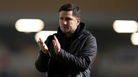 Crewe manager Lee Bell claps the crowd after a game