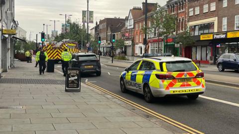 A police car and fire engine on High Street North in Dunstable, where a fire engine and a vehicle are stopped as officers speak to people at the scene.