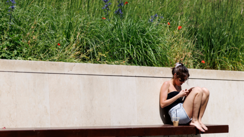 A person enjoys the sunshine and warm weather at United States Embassy Park in London