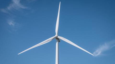 White, three-blade turbine against a blue sky