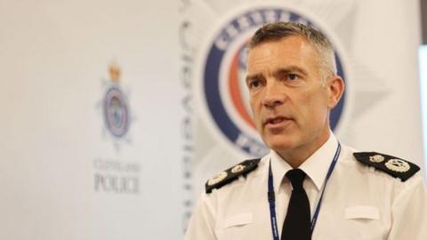 Head-and-shoulder image of Mark Webster. He is looking to his right and is wearing a police uniform, including a white shirt and black tie. He has short greying hair. Cleveland Police's logo can be seen in the background.