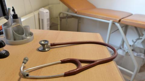 A stethoscope on a brown desk in a surgery