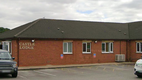 The exterior of Castle Lodge Independent Hospital in Bransholme. It is a long, single-storey building with windows. A car park is in front of it.