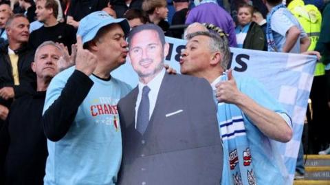 Two Coventry City fans kiss a cardboard cut-out of Frank Lampard 