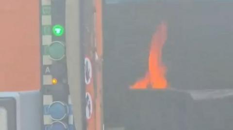 A flame from inside the bin lorry as it catches fire.