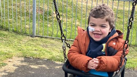 Small boy in swing smiling 