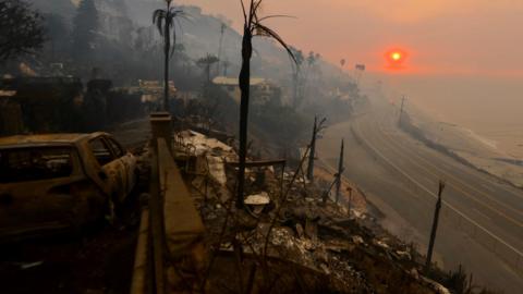 Burned out coast road with low range sun and burnt car in foreground