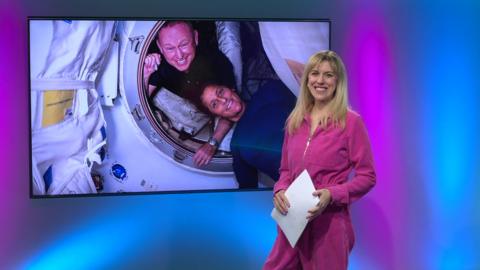 Jenny in the studio with astronauts in the screen