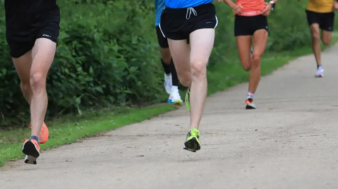 Legs with trainers on run down a path outdoors