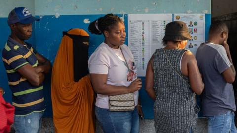 Five people queue outside a polling station in Maputo on 9 October.